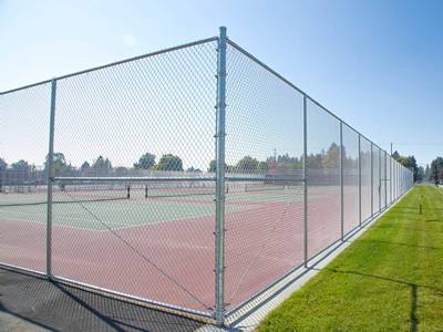 Ogrodzone kortami tenisowymi ogrodzenie z podwójnymi bramkami.